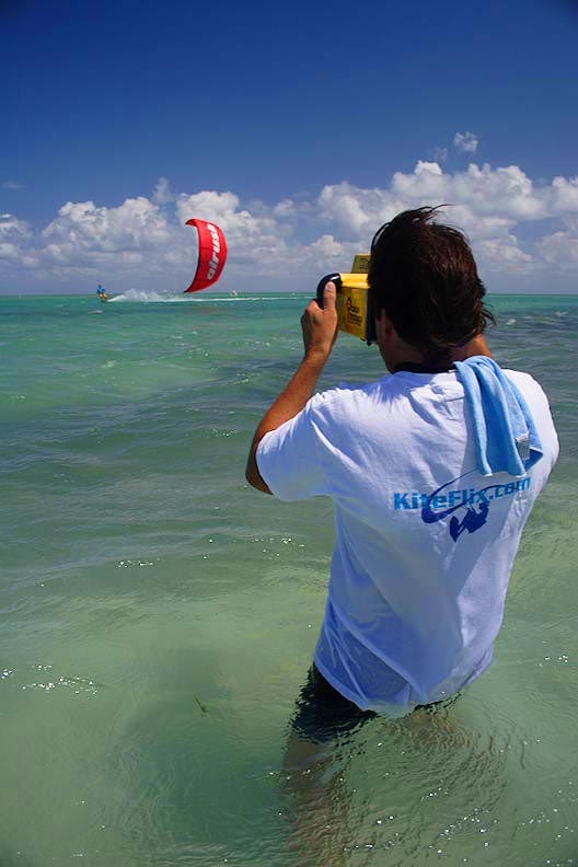 George filming kitesurfing in the ocean with a homemade waterproof camera rig, wearing a KiteFlix.com shirt.